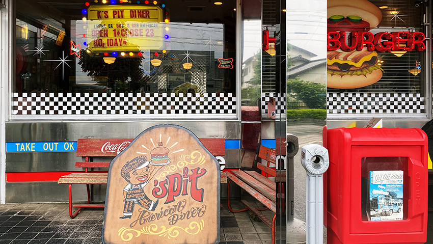 ケーズピットオリジナルキャラクターが描かれたアメリカンレトロな看板やポスト風のオブジェがエントランスに飾られている